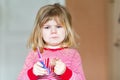 Little cute toddler girl making experiment with scissors and cutting hairs. Funny baby child cuts her pony herself at Royalty Free Stock Photo