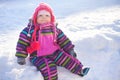 Little baby sitting on a snow, winter day.