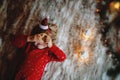 Little cute toddler girl under Christmas tree, eating reindeer cookie and dreaming of Santa at home, indoors