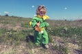 Little cute toddler walking in the middle of meadow with fox toy in green clothes with yellow scarf Royalty Free Stock Photo