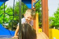 Little cute two year old caucasian toddler boy playing laughing hugging with his mother on playground in city park. Summer day Royalty Free Stock Photo