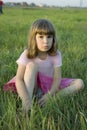 Little cute upset girl sitting in grass