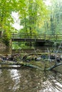 Little dam infront of an old bridge over a little creek or forest brook with a big branch in the water and rocks with foliage Royalty Free Stock Photo