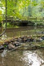 Little dam infront of an old bridge over a little creek or forest brook with a big branch in the water and rocks with foliage Royalty Free Stock Photo