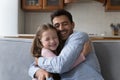 Little daughter cuddles tightly her stepdad seated on sofa Royalty Free Stock Photo