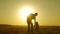 Little daughter and dad walk around field holding hands. child holds father`s hand. dad and baby are resting in the park Royalty Free Stock Photo