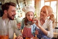 A little daughter eating paprika while preparing a meal at home with her parents. Family, together, home Royalty Free Stock Photo