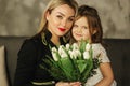 Little daughter give to mother bouquet of flowers. Mom and daughter at home. Bouquet of flowers on 8th of march