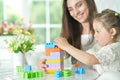 Little daughter and happy mother playing with colorful plastic blocks at home Royalty Free Stock Photo