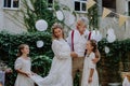 Little daughter holding wedding dress train her mother at backyard party. Royalty Free Stock Photo
