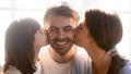 Little daughter and mother kissing happy father husband on cheeks Royalty Free Stock Photo