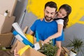 Little daughter with paintbrush hugs father, who keeps box of tools and things.