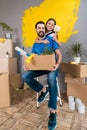 Little daughter with paintbrush hugs father, who keeps box of tools and things.