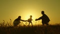 Little daughter with parents jumping at sunset. Silhouettes of mom dad and baby in the rays of dawn. Family concept