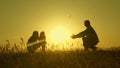 Little daughter with parents jumping at sunset. Silhouettes of mom dad and baby in the rays of dawn. Family concept