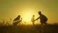 Little daughter with parents jumping at sunset. Silhouettes of mom dad and baby in the rays of dawn. Family concept