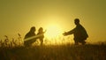 Little daughter with parents jumping at sunset. Silhouettes of mom dad and baby in the rays of dawn. Family concept