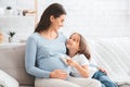 Little daughter putting baby little boots on expecting mother tummy Royalty Free Stock Photo