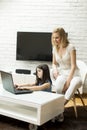 Little daughter sits on the floor and use a laptop