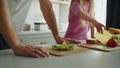 Little daughter stands in the kitchen at the table and helps her father to prepare and fold a sandwich for breakfast