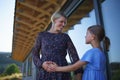 Little daughter stroking pregnant belly his mother, in front of their new wooden house.