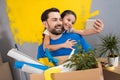 Little daughter using smartphone does selfie with her father who keeps box of tools and things.