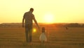 Little daughter walks with her father in a meadow holding hands. child holds father`s hand. family walks in evening out Royalty Free Stock Photo