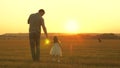 Little daughter walks with her father in a meadow holding hands. child holds father`s hand. family walks in evening out Royalty Free Stock Photo