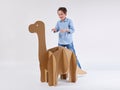 Little dreamer boy playing with a cardboard dinosaur Brontosaurus. Childhood. Fantasy, imagination.