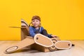 Little dreamer girl playing with a cardboard airplane. Childhood. Fantasy, imagination.