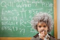 Little Einstein thinking in front of chalkboard Royalty Free Stock Photo