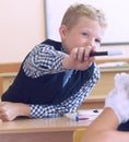 Little elementary school student boy tries to disturb the girl during the lesson. Boy tries to reach the girl`s with