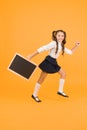 Little and energetic. Little child carrying blackboard on yellow background. Little schoolgirl with black-board for