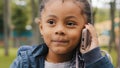 Little ethnic girl talking on mobile phone outdoors portrait funny multiracial child answer telephone call small African Royalty Free Stock Photo