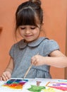 Little european girl painting at table indoors.