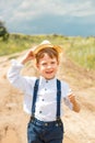 Little farmer on a summer field, cute little boy in a straw hat. boy in a hat with a flower stands in a field. portrait of a Royalty Free Stock Photo