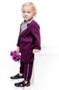 Little fashionable boy in an elegant burgundy suit and with a bouquet of flowers in his hands on a white background. The boy is Royalty Free Stock Photo