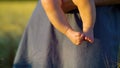 Little feet of baby sitting on hands of mother in rural landscape