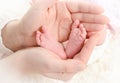 Little feet of newborn baby in the hands of his mother