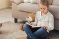 Little female child reading book while sitting on the carpet Royalty Free Stock Photo