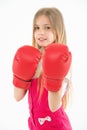 Little fighter before combat. Girl with long blond hair wearing huge red boxing gloves, sport concept. Kid in pink