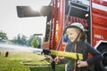 Little fireman holding firehose nozzle and splashing water Royalty Free Stock Photo