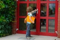 The little first grader opens a door of school. Royalty Free Stock Photo