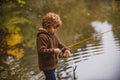 Little fisherman. Child boy fishing in overalls from a dock on lake or pond. Royalty Free Stock Photo