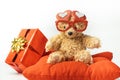 Little fluffy teddy bear wearing red heart shaped glasses and holding red balloon. Happy Valentine\'s Day. Presents in a red Royalty Free Stock Photo