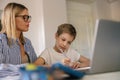 Focused mom helping her son doing homework studying online using laptop in home Royalty Free Stock Photo
