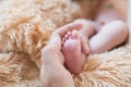 Little foot in hand. Father holding the legs of a newborn in his hands. Mom cares for the baby after taking a bath. Parents to Royalty Free Stock Photo