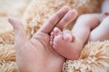 Little foot in hand. Father holding the legs of a newborn in his hands. Mom cares for the baby after taking a bath. Parents to Royalty Free Stock Photo