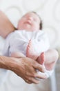 Little foot in hand. Father holding the legs of a newborn in his hands. Mom cares for the baby after taking a bath. Parents to Royalty Free Stock Photo