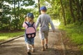 Little friends children hold hands and walk along path in park on summer day. boy and girl are walking in park outdoors Royalty Free Stock Photo